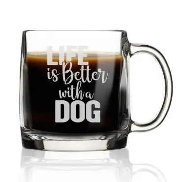 Clear coffee mug with Life is Better with a Dog text, filled with dark coffee, isolated on white background.