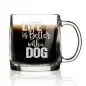 Clear coffee mug with Life is Better with a Dog text, filled with dark coffee, isolated on white background.