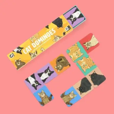 Cat Dominoes set on a pink background featuring illustrated cat designs on the tiles and packaging.
