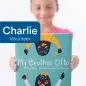 Child holding My Brother Otto book, smiling, volunteer badge with Charlie text.