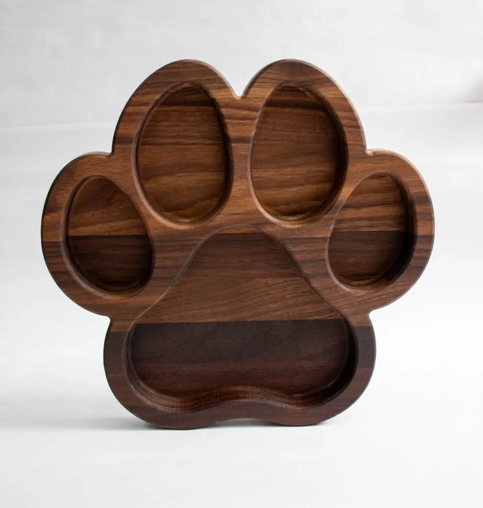 Wooden paw-shaped serving tray with multiple sections on a white background.
