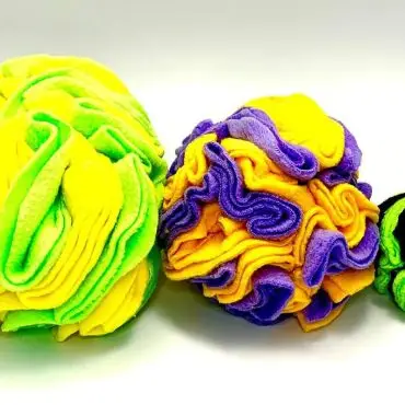 Brightly colored, textured fleece balls in yellow, green, purple, and black on a white background.