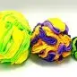 Brightly colored, textured fleece balls in yellow, green, purple, and black on a white background.