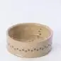Beige ceramic pet bowl with paw print design on a white background.