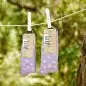 Purple Socks That Save Dogs hanging on a line outdoors, featuring paw prints and eco-friendly tags.