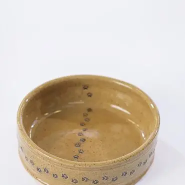 Handcrafted ceramic bowl with paw print design on light background. Ideal for pet lovers and home decor.