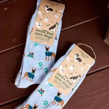 Blue socks with dog patterns, labeled socks that save dogs, placed on a wooden surface.