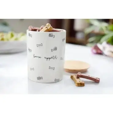 Ceramic jar with bone appétit design, filled with dog treats, on a kitchen counter.