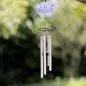 Memorial wind chime with paw print sign, hanging outdoors with blurred green background.