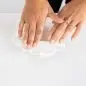 Hands rolling white clay on a table, creating crafts.