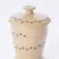 Speckled ceramic jar with paw print design and lid, beige color, isolated on white background.