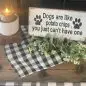 Decorative sign with paws, reads Dogs are like potato chips, you just can't have one, candle and greenery nearby.