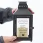Man holding a black lantern with an engraved heartfelt message about a loyal companion and pawprints.