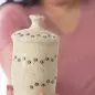 Smiling woman holding decorative ceramic jar with paw prints, focus on jar.