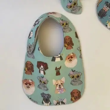Baby bib featuring cute dog illustrations on a blue background, perfect for mealtime and keeping clothes clean.
