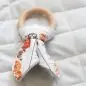 Wooden teething ring with animal-patterned fabric on a quilted background, ideal for baby care.