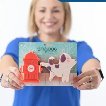 Smiling woman holding Dirty Dog kitchen sponges shaped like a dog and fire hydrant, labeled Kelly Jo Staff.