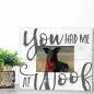 Decorative frame with dog image and You had me at woof text beside a plant on a tabletop.