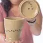 Woman holding handcrafted ceramic mug with lid, showcasing unique design and craftsmanship.