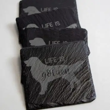 Set of black coasters engraved with Life is golden and a retriever silhouette, perfect for dog lovers.