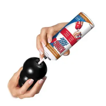 Person filling a dog toy with peanut butter paste for a fun and engaging pet treat activity.