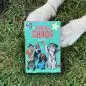 Canine Chaos card game on grass with a dog's paws nearby, featuring illustrated dogs dressed as celebrities.