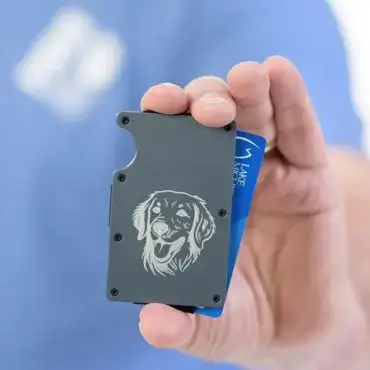 Hand holds wallet with dog engraving and visible blue card, showcasing a stylish and functional design.