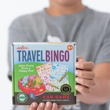 Child holding Eeboo Travel Bingo box, a fun car game for kids aged 4+, enhancing travel enjoyment and engagement.