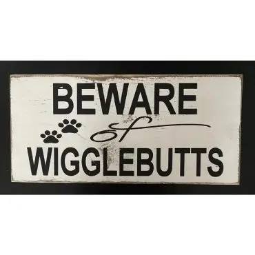 Beware of Wigglebutts sign with paw prints, playful warning for dog lovers.