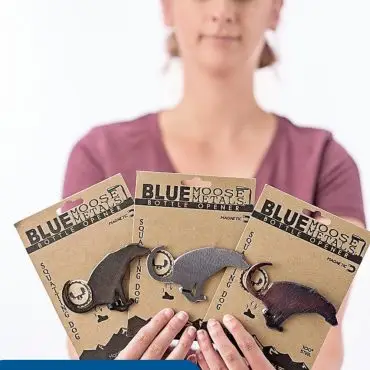 Person holding Blue Moose Metals bottle openers in packaging, wearing name tag reading Megan, Staff.