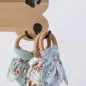 Colorful baby bibs hanging on a wooden hook shaped like a bone with a paw print.
