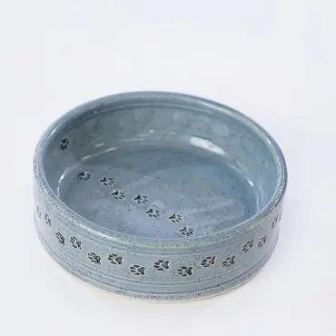 Blue ceramic pet bowl with paw print design on a white background.