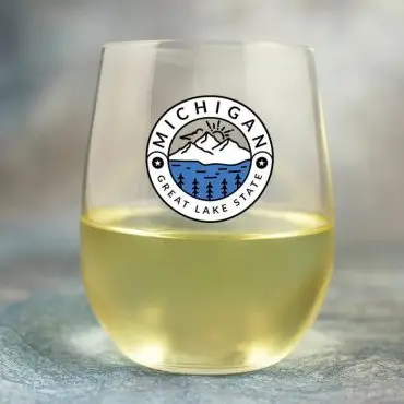 Clear glass with Michigan Great Lake State design, containing white wine, on a blue background.