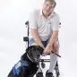 Man in wheelchair with assistance dog in blue vest, both smiling. Empowerment and support through service animals.