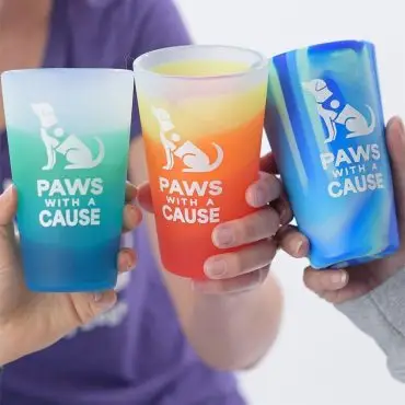 Colorful Paws With a Cause cups being held, featuring vibrant blue and orange hues.