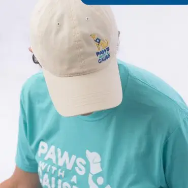 Person in Paws With a Cause cap and shirt, labeled Staff, highlighting assistance and facility dog program.