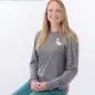 Smiling woman in gray shirt and teal pants seated on stool, with name tag reading Melissa Staff.