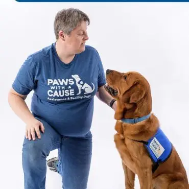 Person with assistance dog in Paws With a Cause attire, highlighting service dog teamwork and support.