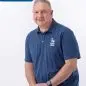 Man in blue polo with Paws With a Cause logo, seated, white background. Text reads Chris Staff.