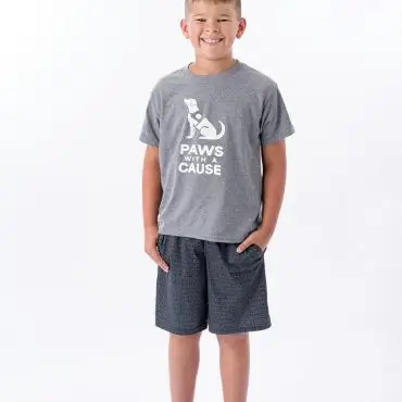 Smiling child wearing a Paws with a Cause T-shirt, shorts, and blue Crocs against a white background.