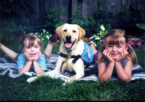 Happy kids with a Labrador retriever lying on a blanket outdoors. Smiling faces and joyful moments in the garden.