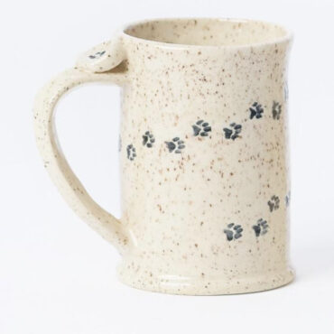 Handcrafted ceramic mug with speckled glaze and paw print design, white background. Perfect for coffee or tea lovers.