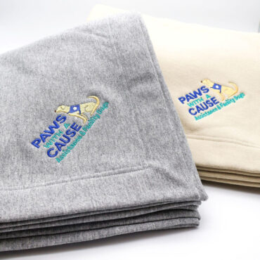 Gray and beige blankets with Paws With a Cause embroidery, featuring assistance dogs logo design.