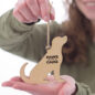 Person holding wooden dog ornament with Paws with a Cause text, symbolizing support for animal charities.