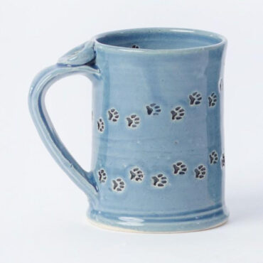 Handcrafted blue ceramic mug with paw print design, perfect for pet lovers. Unique and artistic kitchenware.
