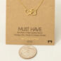 Gold heart and paw necklace on a cardboard background, next to a coin, labeled Must Have 18K gold dipped.