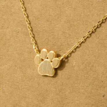 Gold paw print necklace on a chain, set against a textured brown background, perfect for pet lovers.