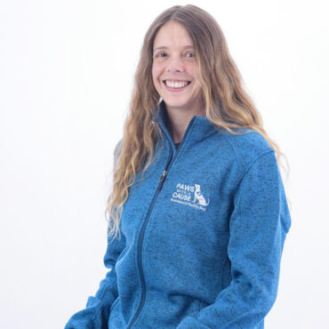 Smiling person in a blue Paws With A Cause jacket sitting casually against a white background.