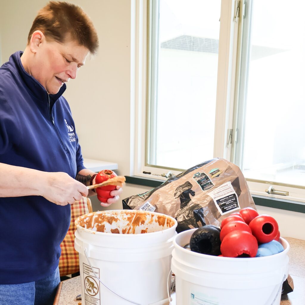 Person filling dog toys with treats in a kitchen, preparing for pet enrichment activities.