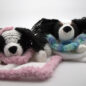 Two cute crochet dog toys wrapped in pastel pink and blue blankets on a white background.